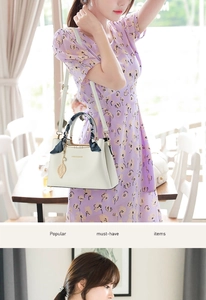 Detail of white tote bag with gold leaf charm and floral scarf wrapped on the handle