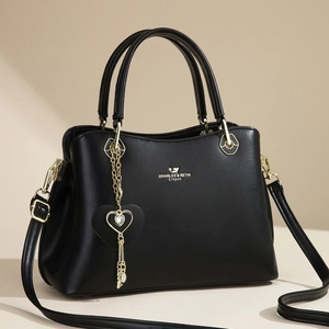 Elegant black leather handbag for women with gold hardware and heart-shaped pendant