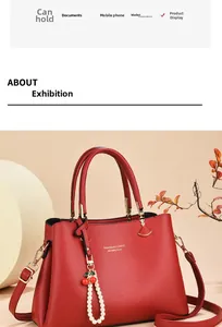 Detail of red pebble leather handbag with gold hardware and cherry pearl charm