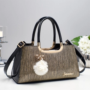 Détail de sac à main noir et doré élégant avec pompon en perles et finitions métalliques