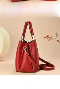 Detailed view of red lychee grain leather handbag with golden hardware and shoulder strap