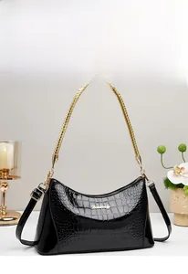 Detail of black faux crocodile leather bag with golden woven handle and metal logo