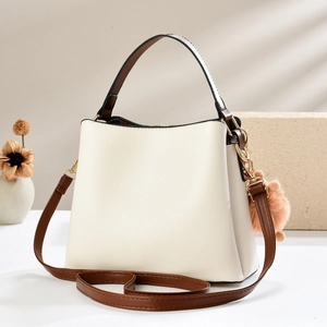 Elegant beige PU leather bucket bag with brown handles and a plush pom-pom charm