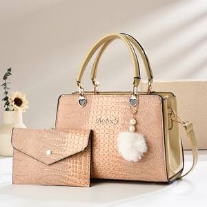 Detailed macro view of beige crocodile embossed leather tote set with pearl pompom charm