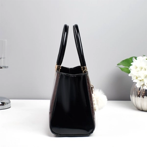 Détail du sac à main en cuir verni noir avec paillettes rouges et pompon blanc doux