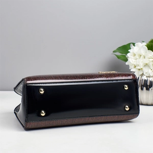 Détail du fond en cuir verni noir brillant avec rivets dorés et tissu scintillant