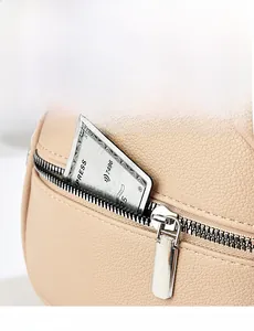 Close-up of cream leather bag showing lychee grain texture and silver zipper pocket