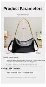 Detail view of black patent leather handbag with crocodile pattern and golden chain handle