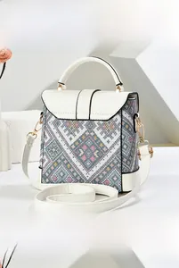 Detail showing colorful geometric jacquard pattern and gold hardware on the crossbody bag