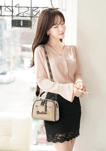 Detail of beige leather handbag with Fashion logo and patterned wide shoulder strap