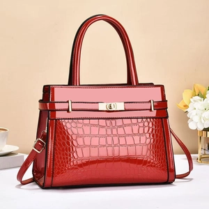 Detail of red faux crocodile leather handbag with golden metal lock and glossy finish