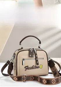 Detail of two-tone handbag showing embroidered fashion patch and decorative zipper puller