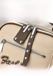 Detailed macro view of beige leather bag with silver double zippers and fashion embroidery