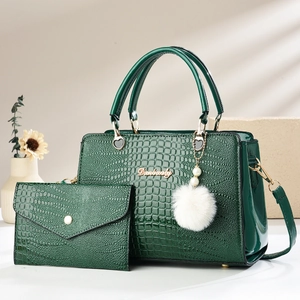 Detail of dark green crocodile texture tote bag with golden logo and pearl keychain