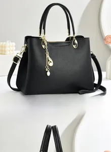 Détail du sac à main noir en cuir grainé avec des finitions métalliques dorées et une chaîne