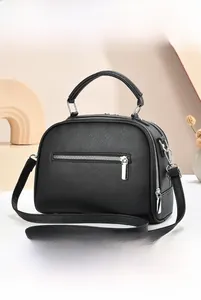 Detail view of black litchi texture handbag with silver zippers and multi-layer storage