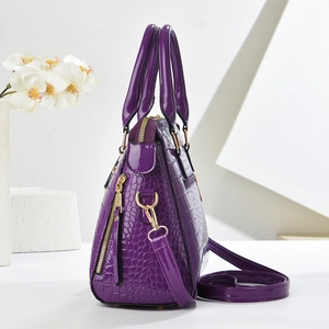 Detail of purple crocodile embossed patent leather handbag with gold hardware
