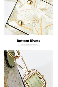 Detailed view of floral embroidery handbag featuring bottom rivets and gold metal hardware