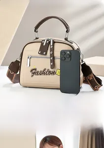 Detail of beige PU leather handbag with contrasting brown trim and wide patterned strap