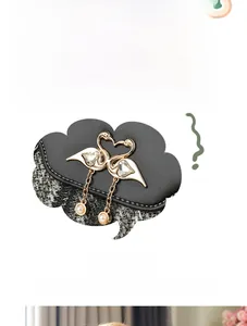 Détail du sac noir texturé avec ornements de cygnes dorés, cristaux et pendentifs perles
