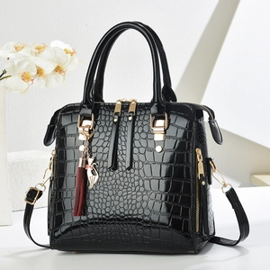 Close-up of black crocodile pattern handbag with gold hardware and cat charm detail