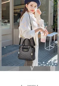Détail d'un sac à main gris foncé avec motif rétro, poignées en cuir et garnitures dorées