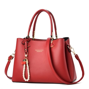 Large red pebbled leather handbag with gold accents and cherry pearl charm