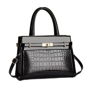 Black crocodile embossed tote bag with gold D-lock and top handle in a minimalist style