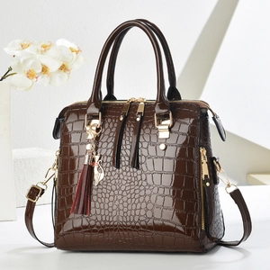 Detail of dark brown faux crocodile leather bag with gold cat charm and tassels