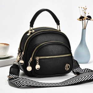 Detail of black pebbled leather handbag with multi-zip layers and striped woven strap