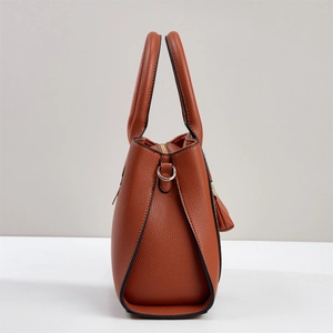Detail of caramel brown faux leather handbag with fine lychee texture and side metal D-ring