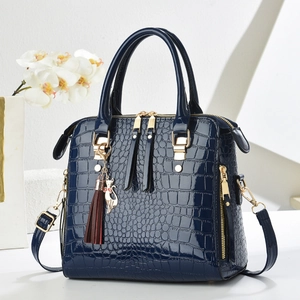 Close-up of dark blue crocodile texture with golden hardware and cat tassel charm