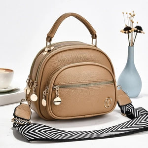 Macro detail of brown leather bag showing three zippers and wave pattern strap