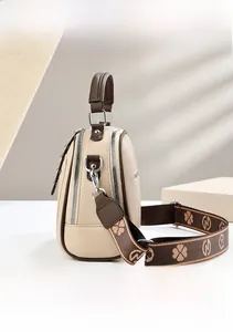 Detail view of double zipper beige crossbody bag with patterned woven strap
