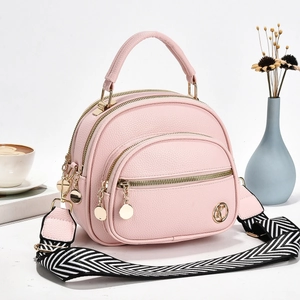 Detail of pink lychee-textured crossbody bag with triple zippers and woven strap