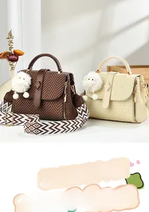 Détail de sacs à main tissés avec larges bandoulières et breloques en peluche blanche