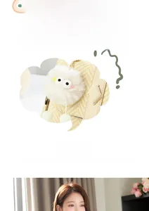 Détail du sac à main tissé beige avec un joli charme de pompon blanc à yeux