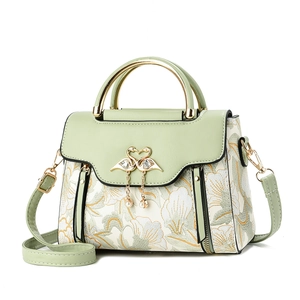 Light green handbag with floral embroidery and golden swan clasp on white background