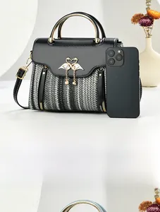 Détail d'un sac bandoulière en tweed avec fermoir flamant rose et poignée dorée près d'un tel