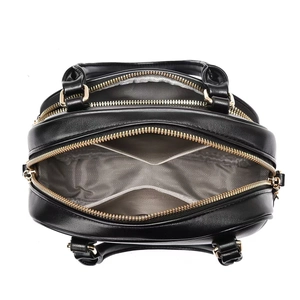 Interior detail of black leather bag showing grey herringbone lining and gold zippers