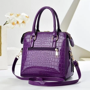 Dettaglio della borsa viola a motivo coccodrillo con texture lucida e finiture dorate