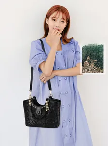 Model posing with a black crocodile pattern handbag featuring a metal chain strap