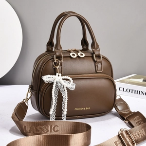 Detail of coffee brown PU leather bag with pearl bow charm and jacquard shoulder strap