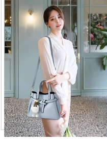 Detail of light blue crossbody bag featuring bow charm and gold hardware on a model