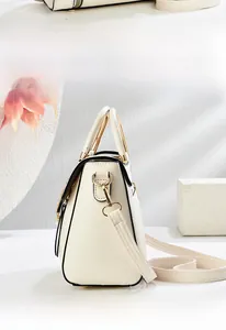 Détail d'un sac bandoulière crème avec poignée dorée et décoration de perles fines