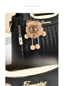 Detail of black leather handbag featuring woven texture and a cute plush bear pendant