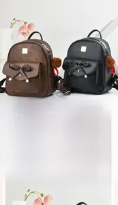 Gros plan sur des sacs à dos en cuir PU marron et noir avec nœuds et pompons en peluche