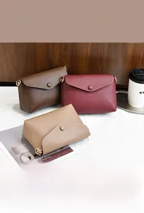Detailed view of three mini textured faux leather clutch bags in brown, red, and khaki colors