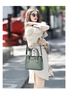 Détail de la texture crocodile embossée vert foncé avec fermoir pivotant doré sur le sac