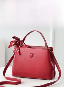 Close-up of red leather bucket bag with heart buckle and decorative silk scarf detail